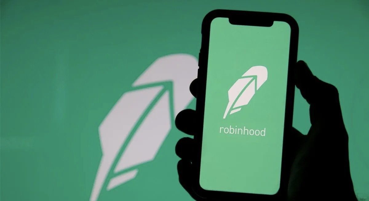 Hand holding a smartphone on the background of the RobinHood logo