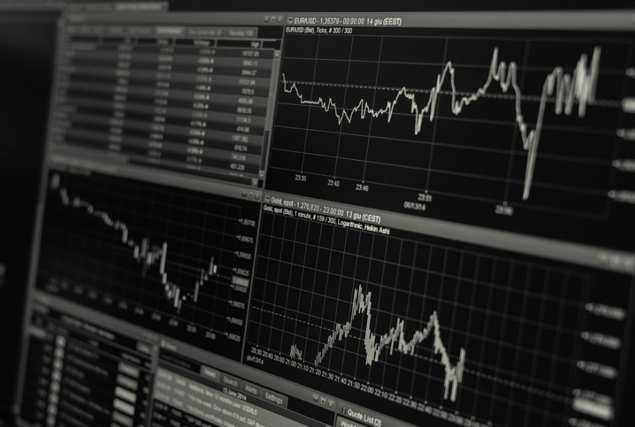 Monochrome image of a multi-monitor trading setup displaying various financial charts and market data