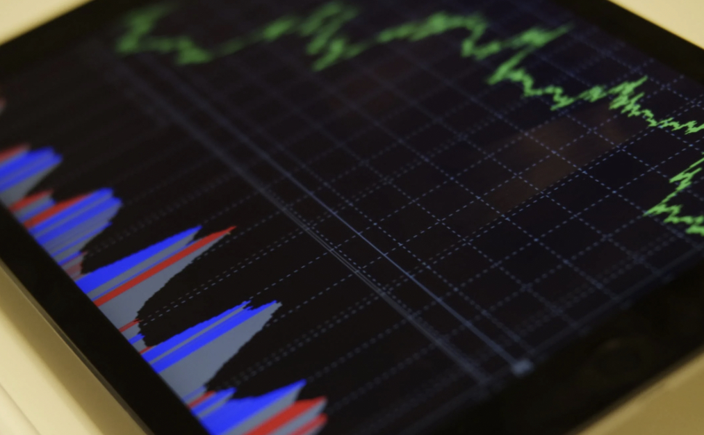 Close-up of a tablet screen showing a detailed stock market graph with various colored lines indicating different data points